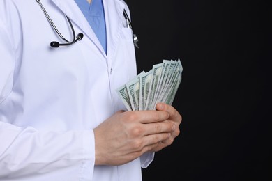 Photo of Corruption concept. Doctor with dollar banknotes on black background, closeup