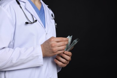 Photo of Corruption concept. Doctor with dollar banknotes on black background, closeup