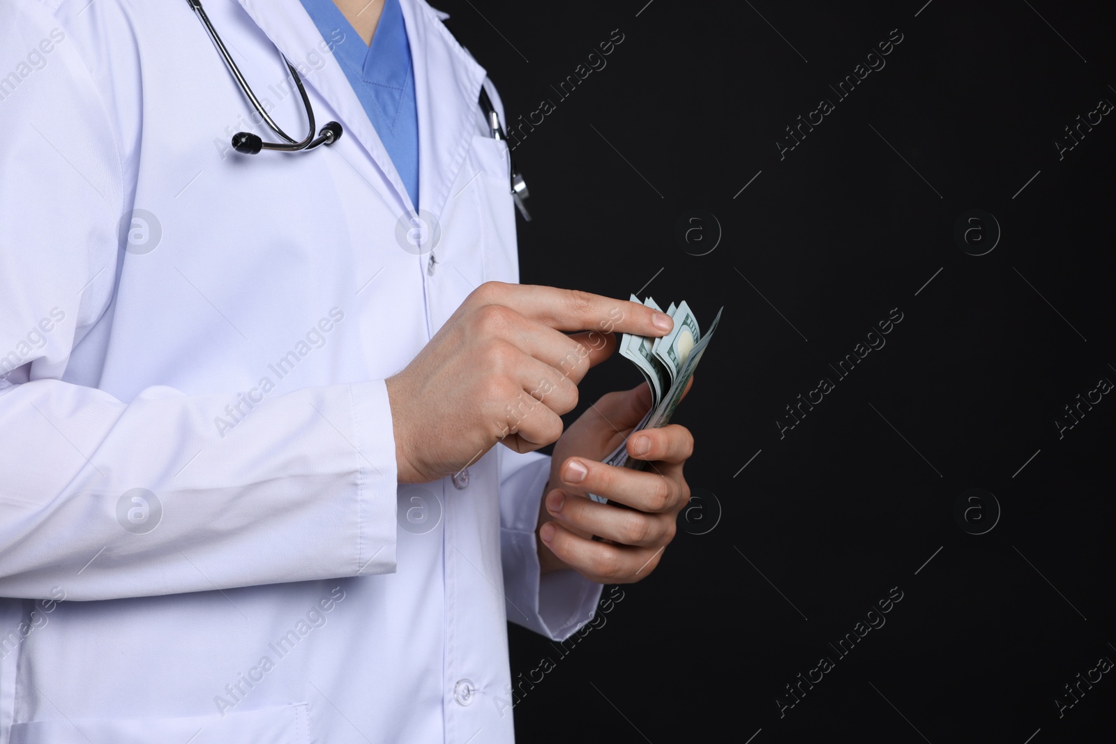 Photo of Corruption concept. Doctor with dollar banknotes on black background, closeup