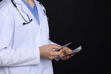 Photo of Corruption concept. Doctor with dollar banknotes on black background, closeup