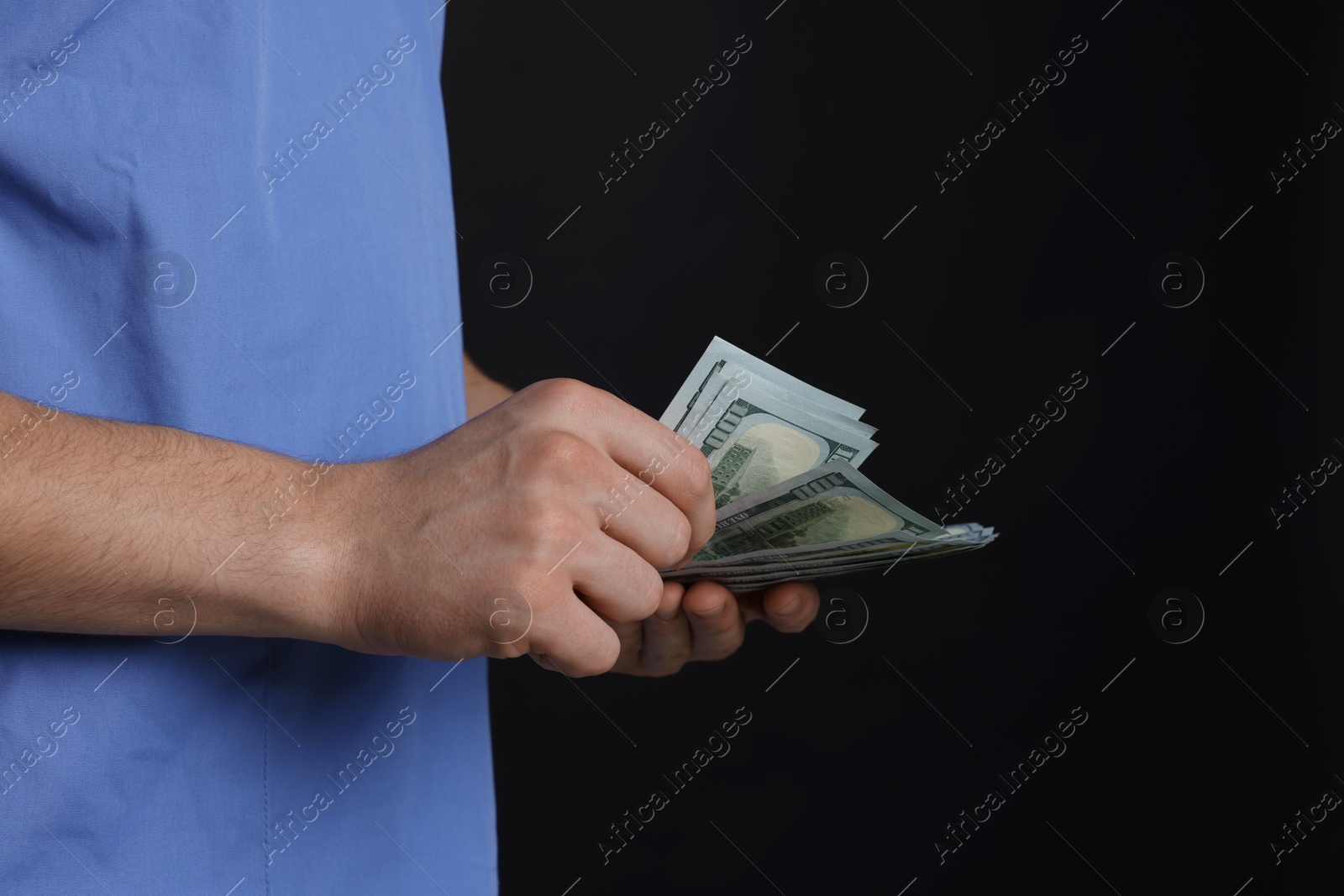 Photo of Corruption concept. Doctor with dollar banknotes on black background, closeup