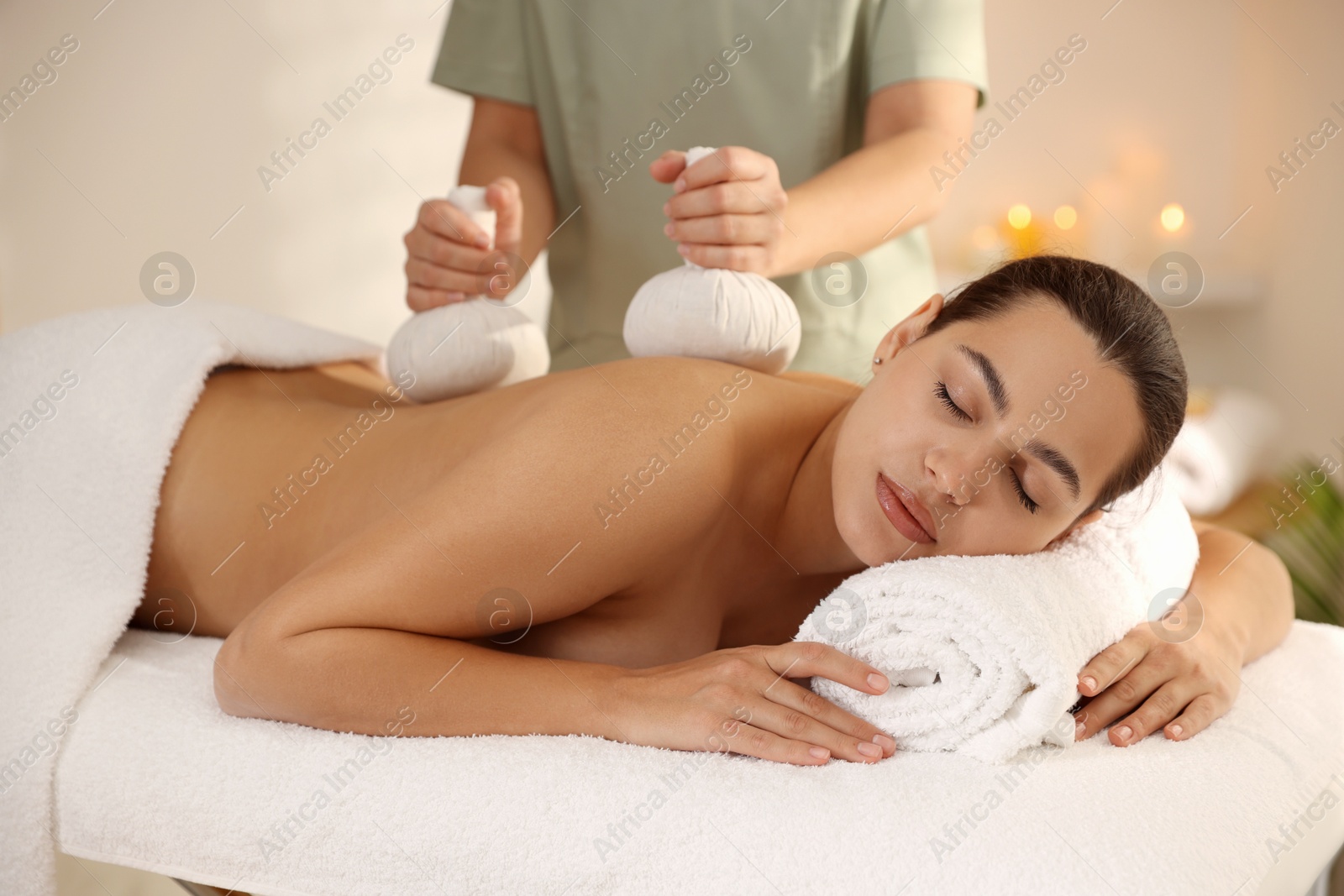 Photo of Woman receiving back massage with herbal bags in spa salon