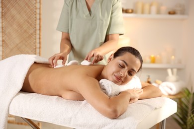 Photo of Woman receiving hot stone massage in spa salon