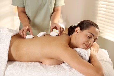 Photo of Woman receiving hot stone massage in spa salon