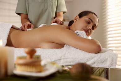 Woman receiving hot stone massage in spa salon