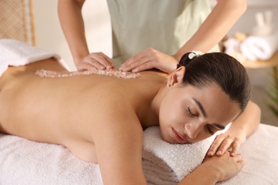 Photo of Woman receiving massage with sea salt in spa salon