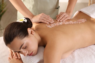 Woman receiving massage with sea salt in spa salon