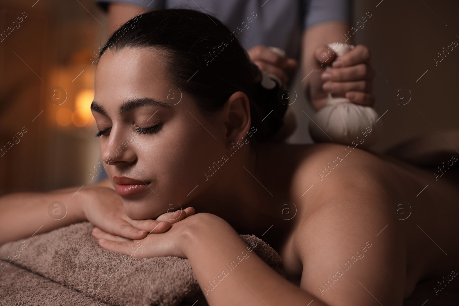 Photo of Woman receiving back massage with herbal bags in spa salon