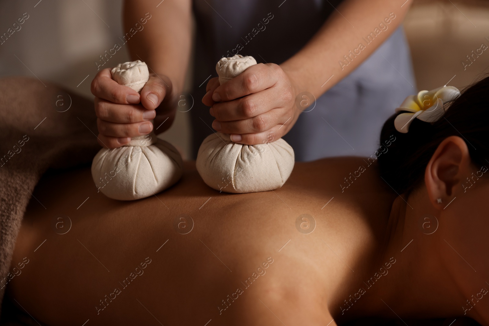 Photo of Woman receiving back massage with herbal bags in spa salon, closeup