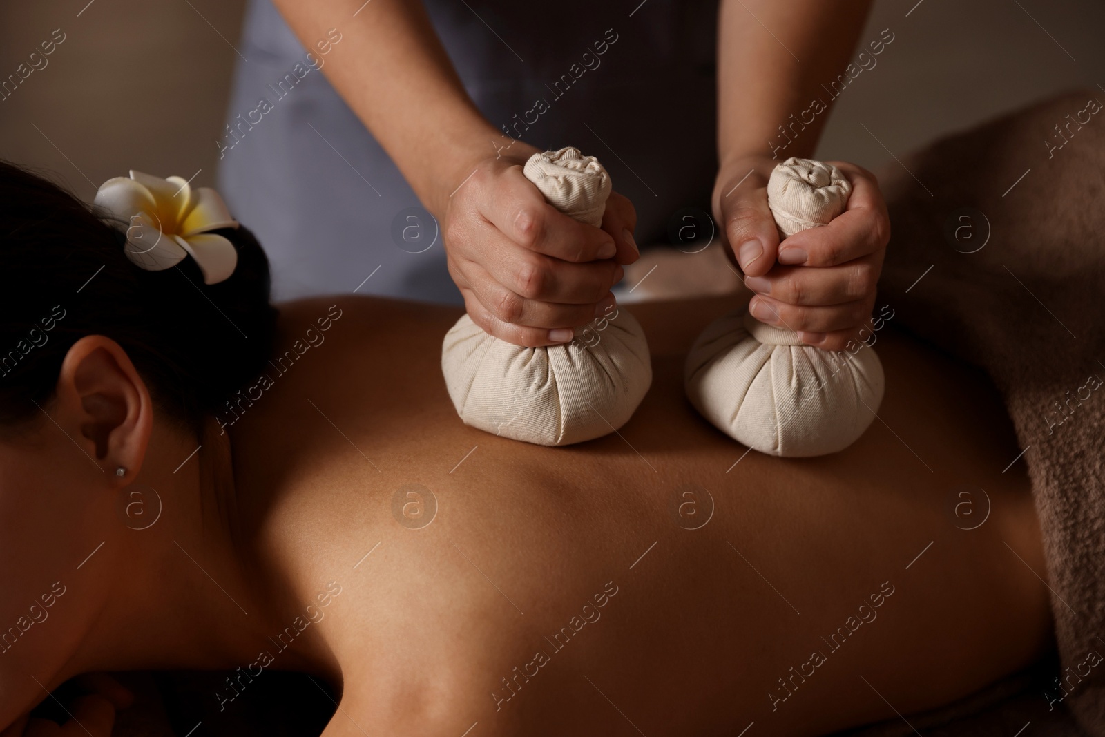 Photo of Woman receiving back massage with herbal bags in spa salon, closeup