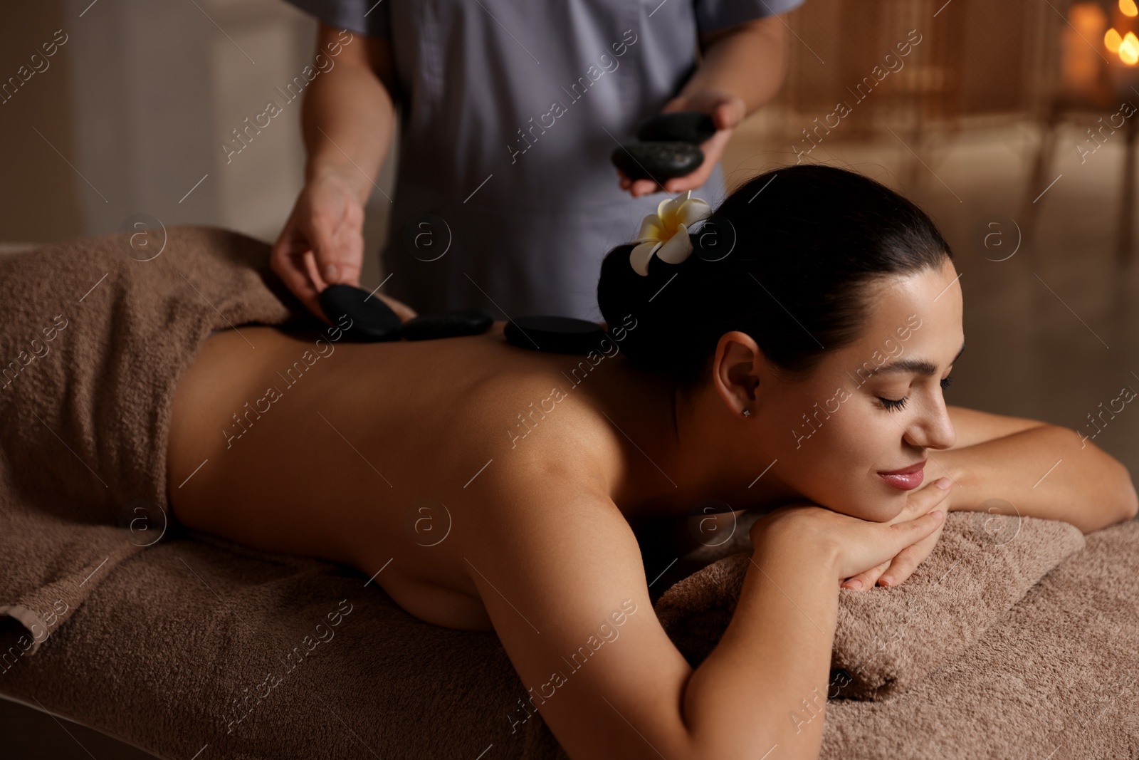 Photo of Woman receiving hot stone massage in spa salon