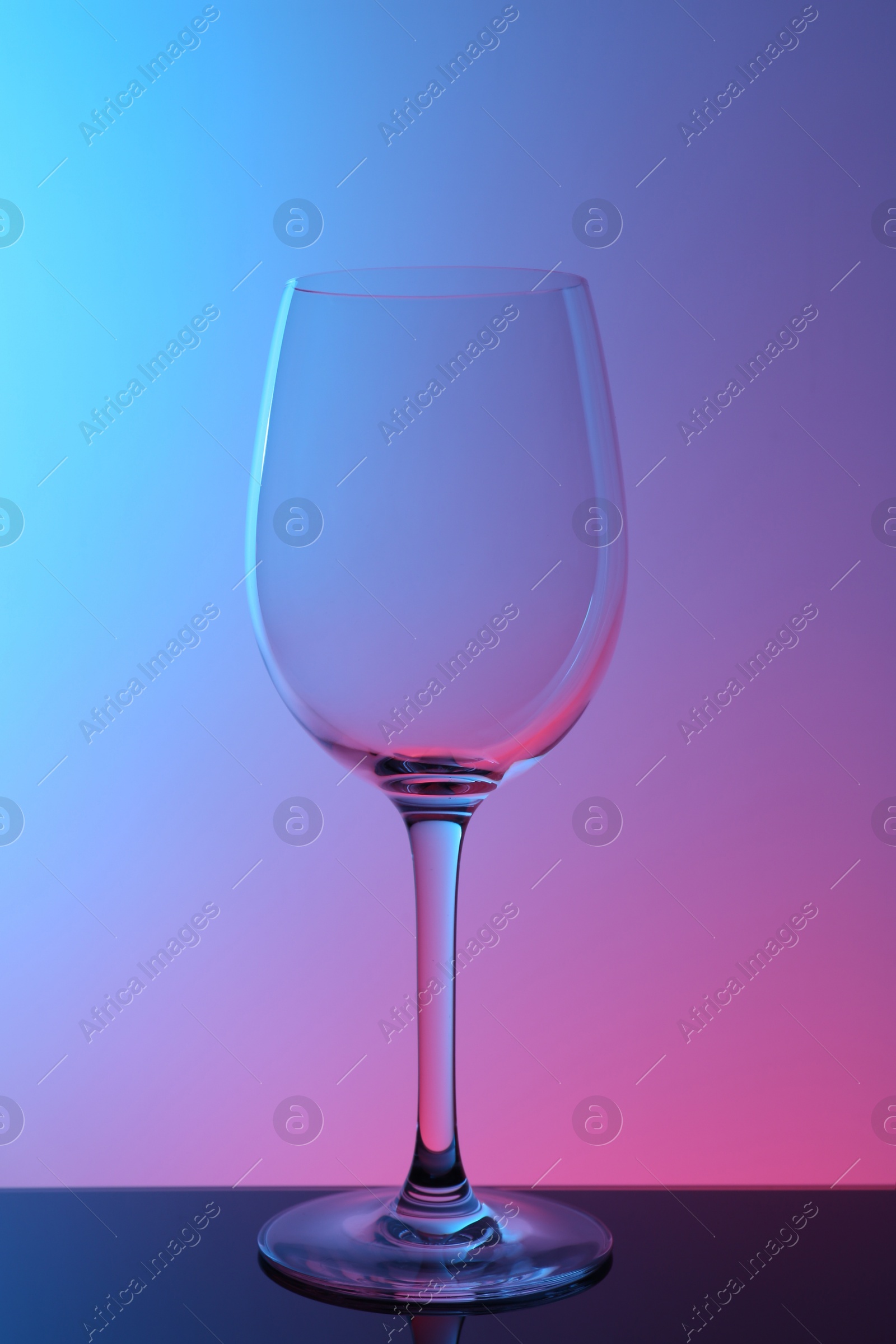 Photo of One empty glass on table against color background