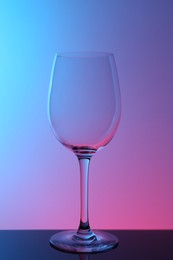 Photo of One empty glass on table against color background