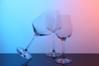 Photo of Empty glasses on table against color background