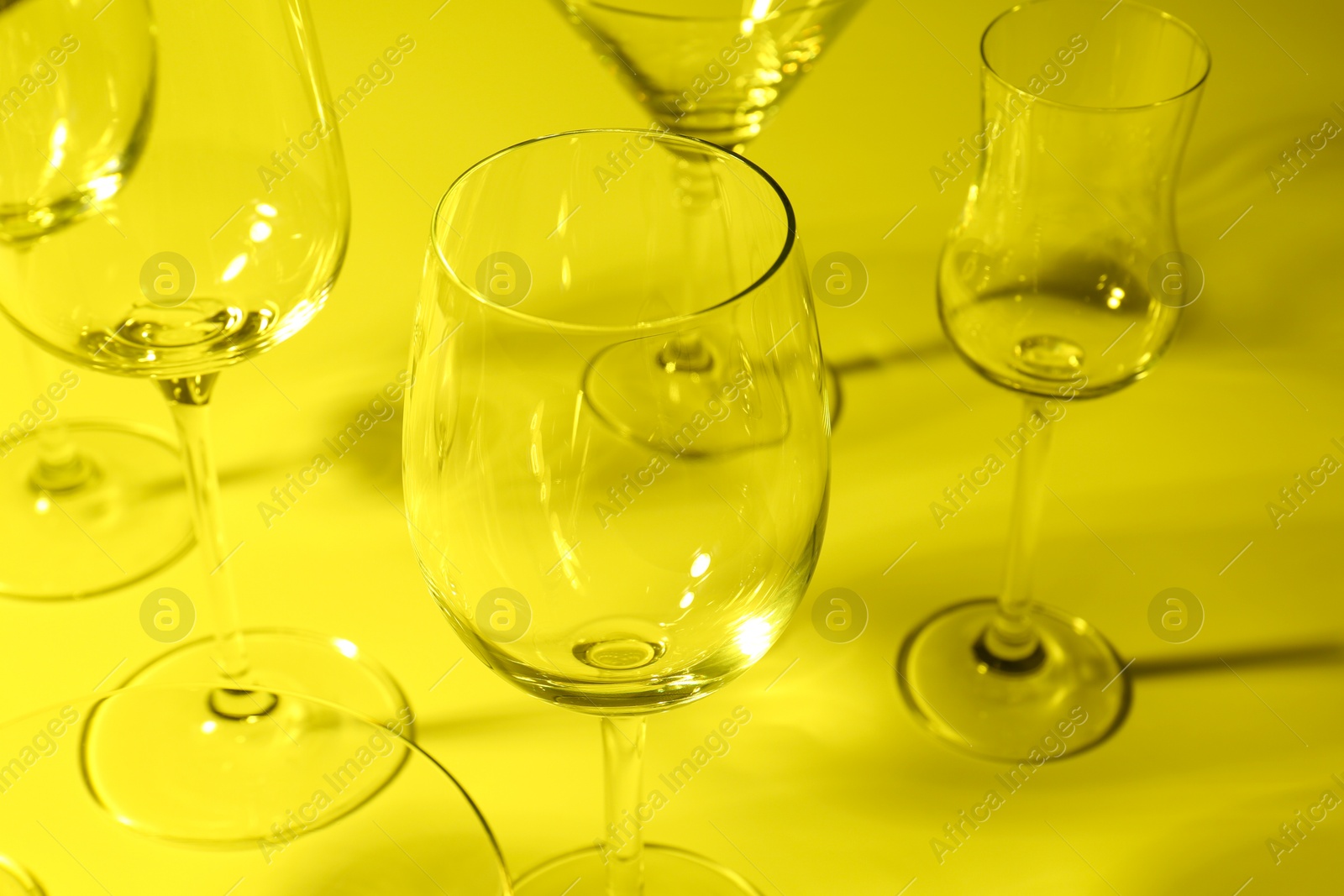 Photo of Empty glasses on yellow background, closeup. Color tone effect