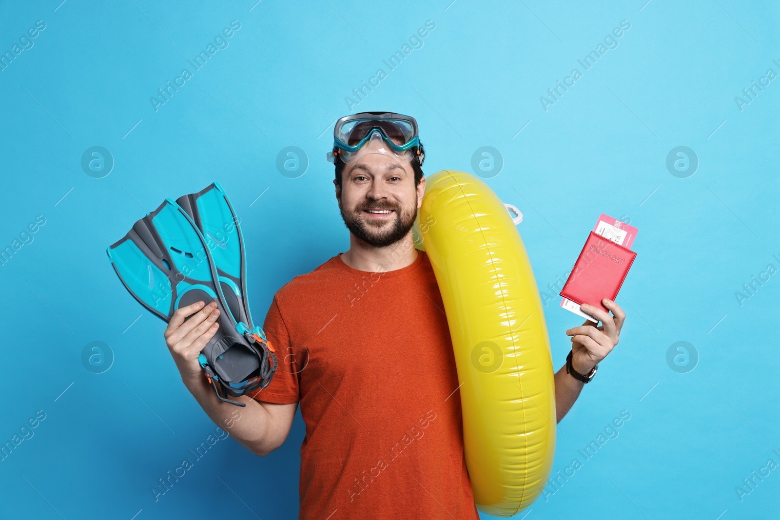 Photo of Traveller with passport, ticket and beach accessories on light blue background