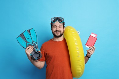 Photo of Traveller with passport, ticket and beach accessories on light blue background