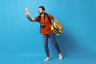 Photo of Traveller with passport, ticket and suitcase on light blue background