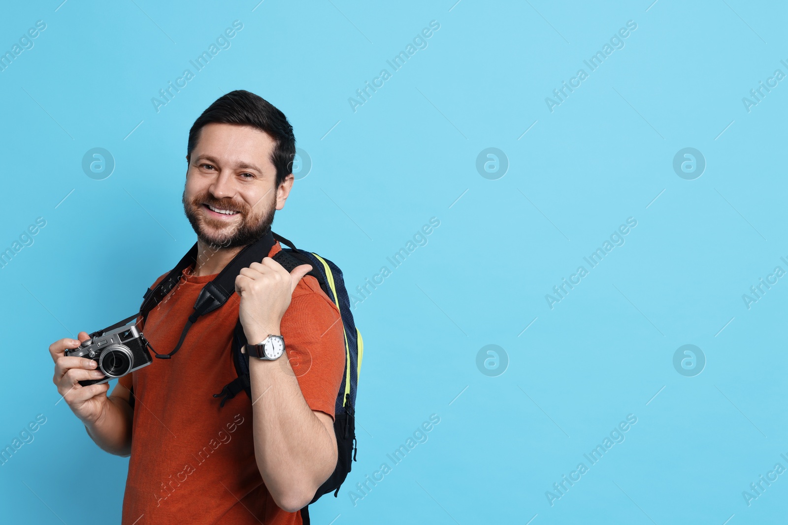 Photo of Traveller with vintage camera on light blue background, space for text