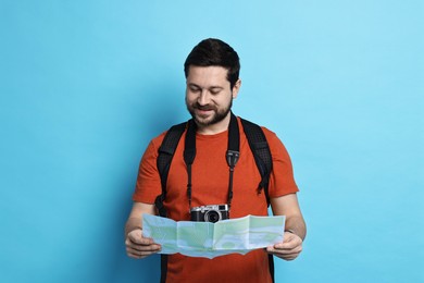 Photo of Traveller with vintage camera and map on light blue background