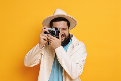 Traveller with vintage camera on orange background