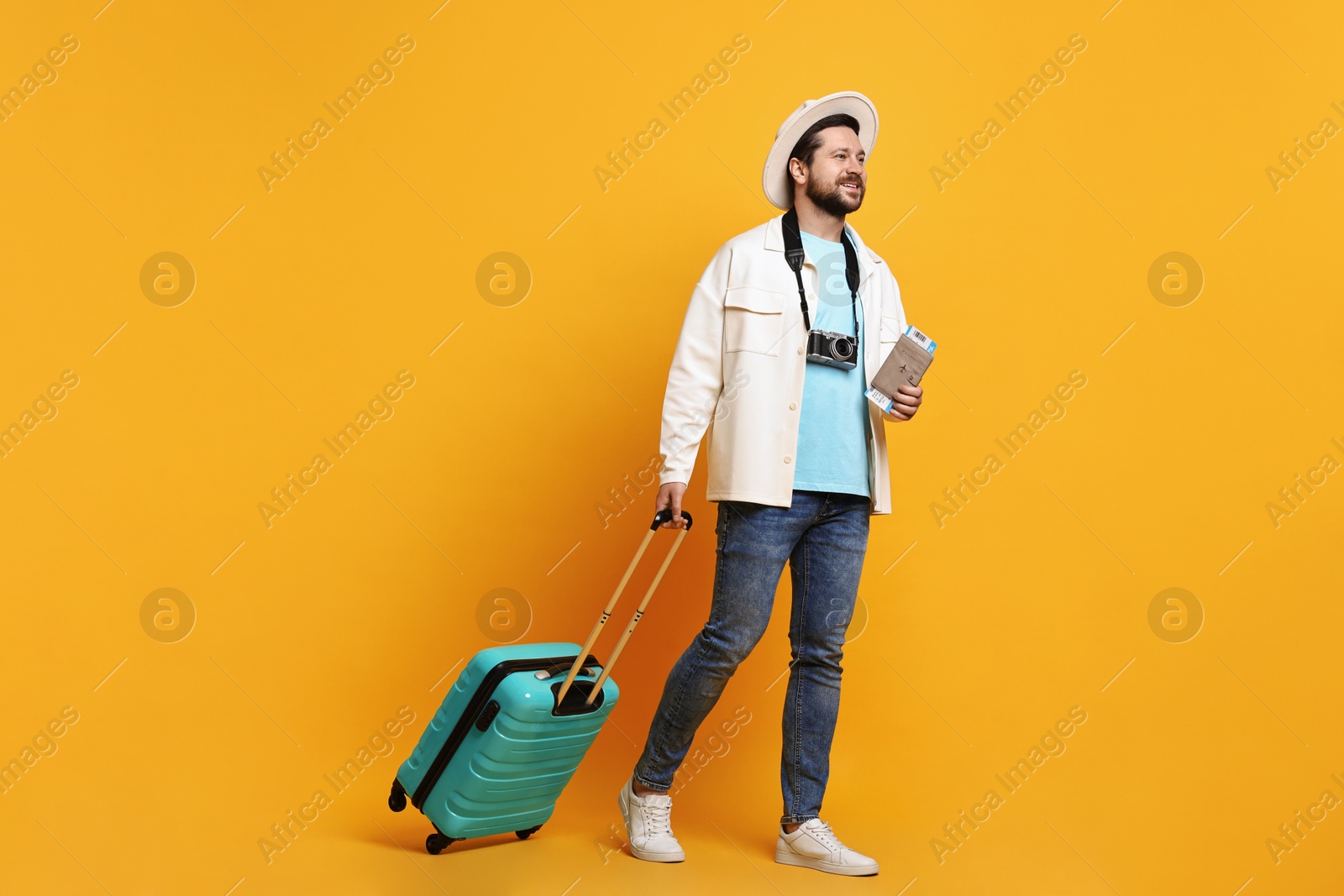 Photo of Traveller with suitcase, passport and ticket on orange background