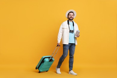 Photo of Traveller with suitcase, passport and ticket on orange background