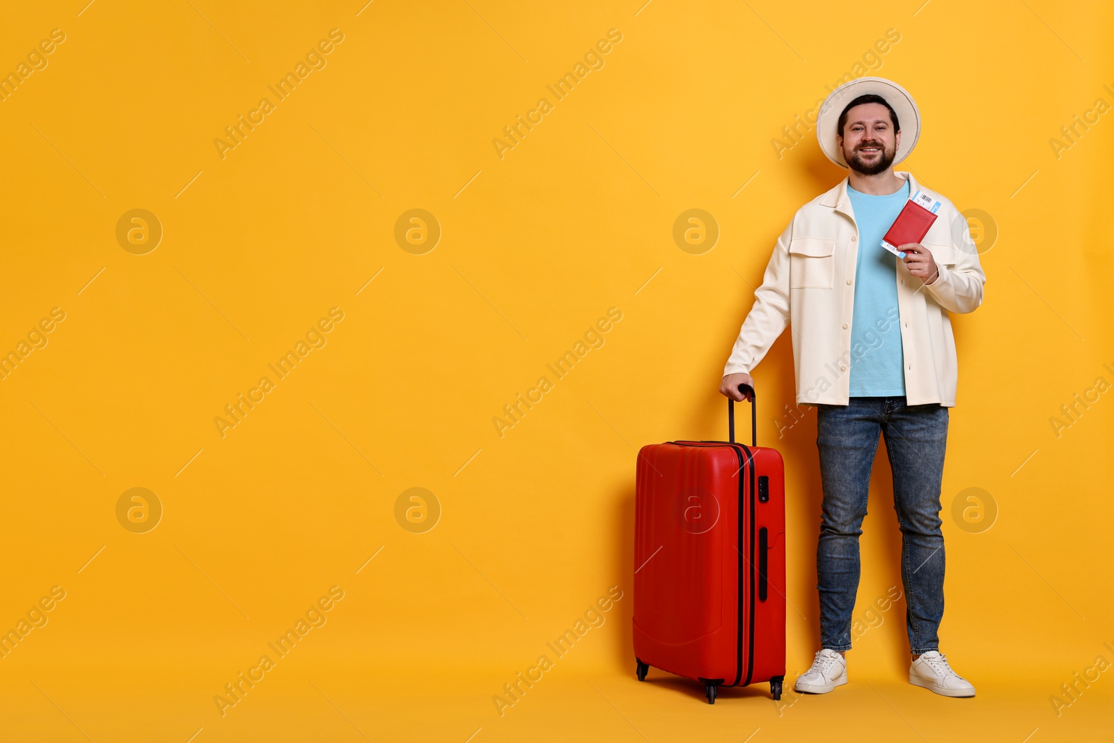 Photo of Traveller with suitcase, passport and ticket on orange background, space for text