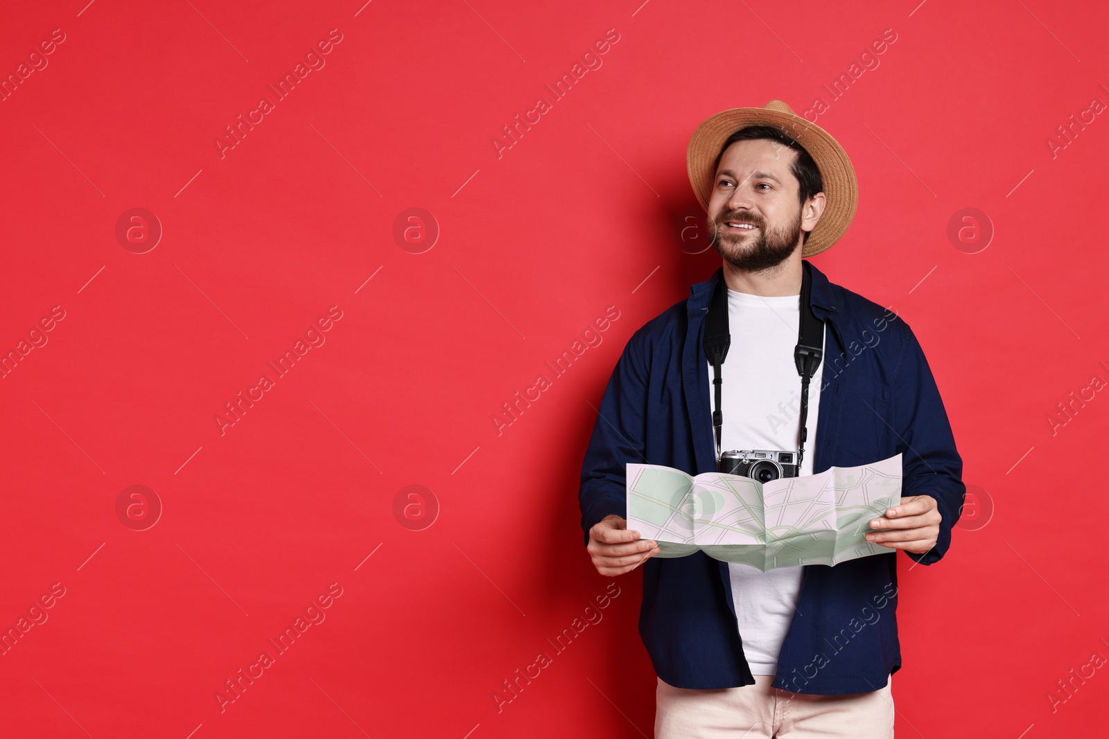 Photo of Traveller with vintage camera and map on red background, space for text