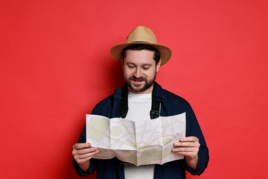 Photo of Traveller in hat holding map on red background