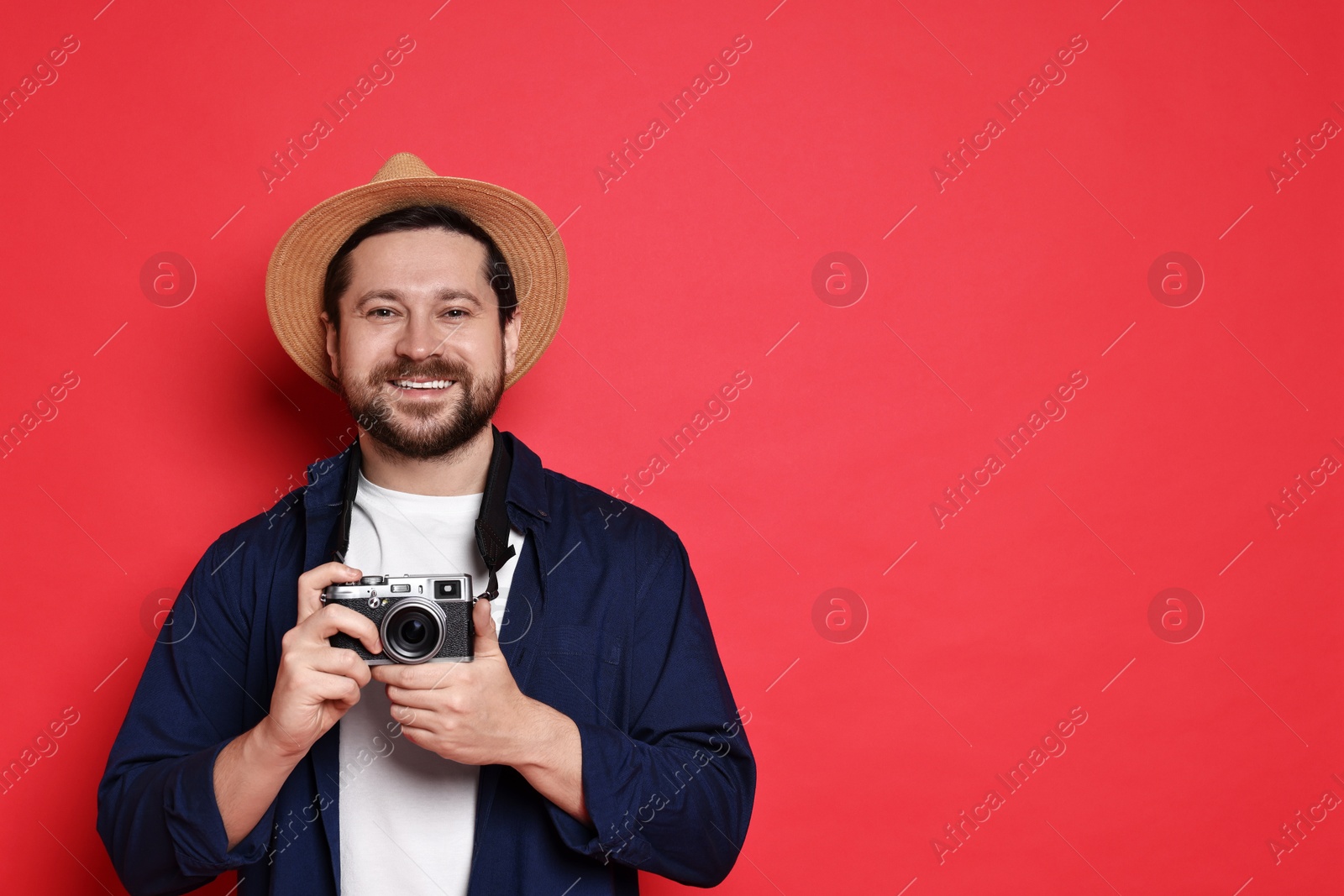 Photo of Traveller with vintage camera on red background, space for text