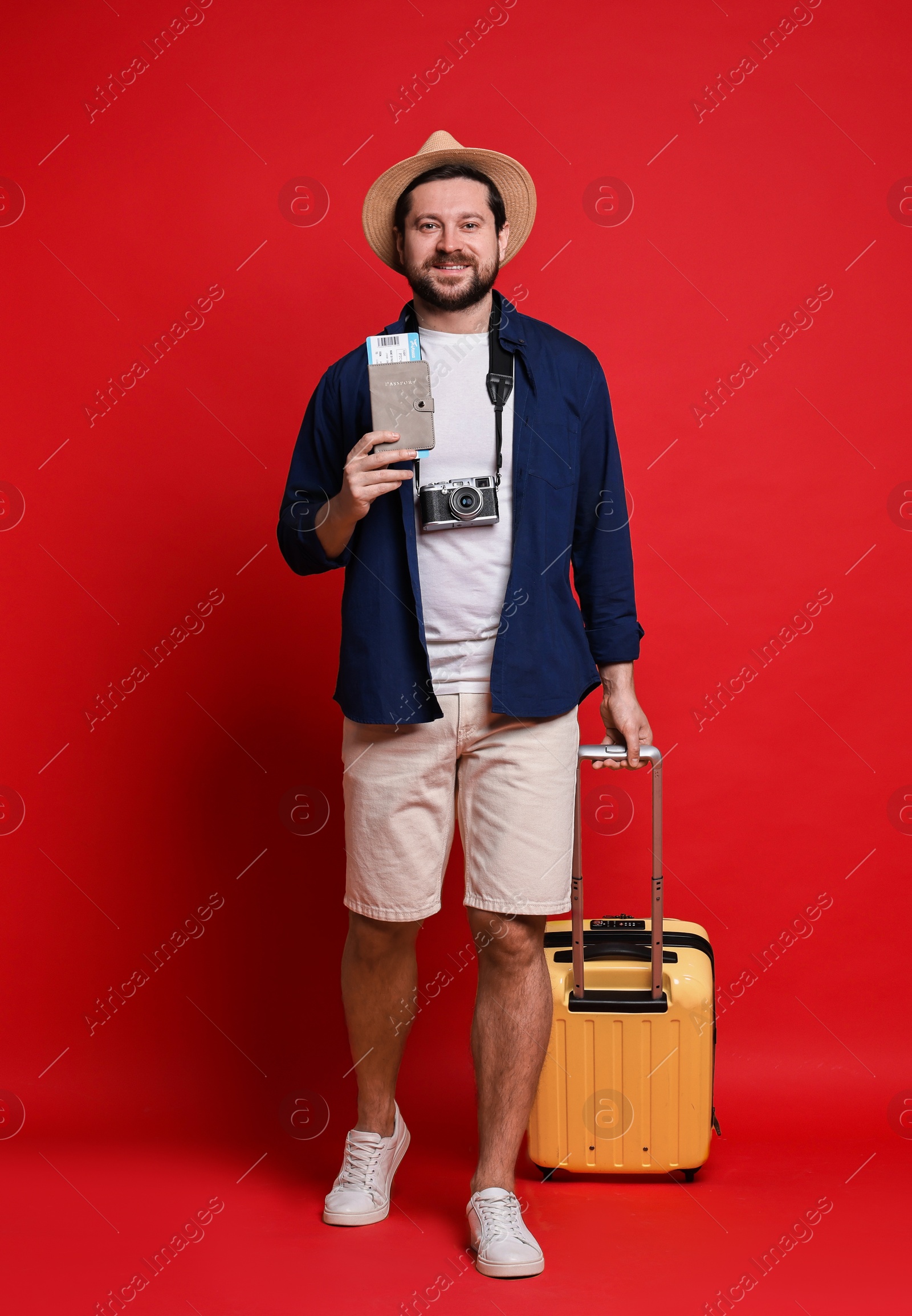 Photo of Traveller with suitcase, passport and ticket on red background