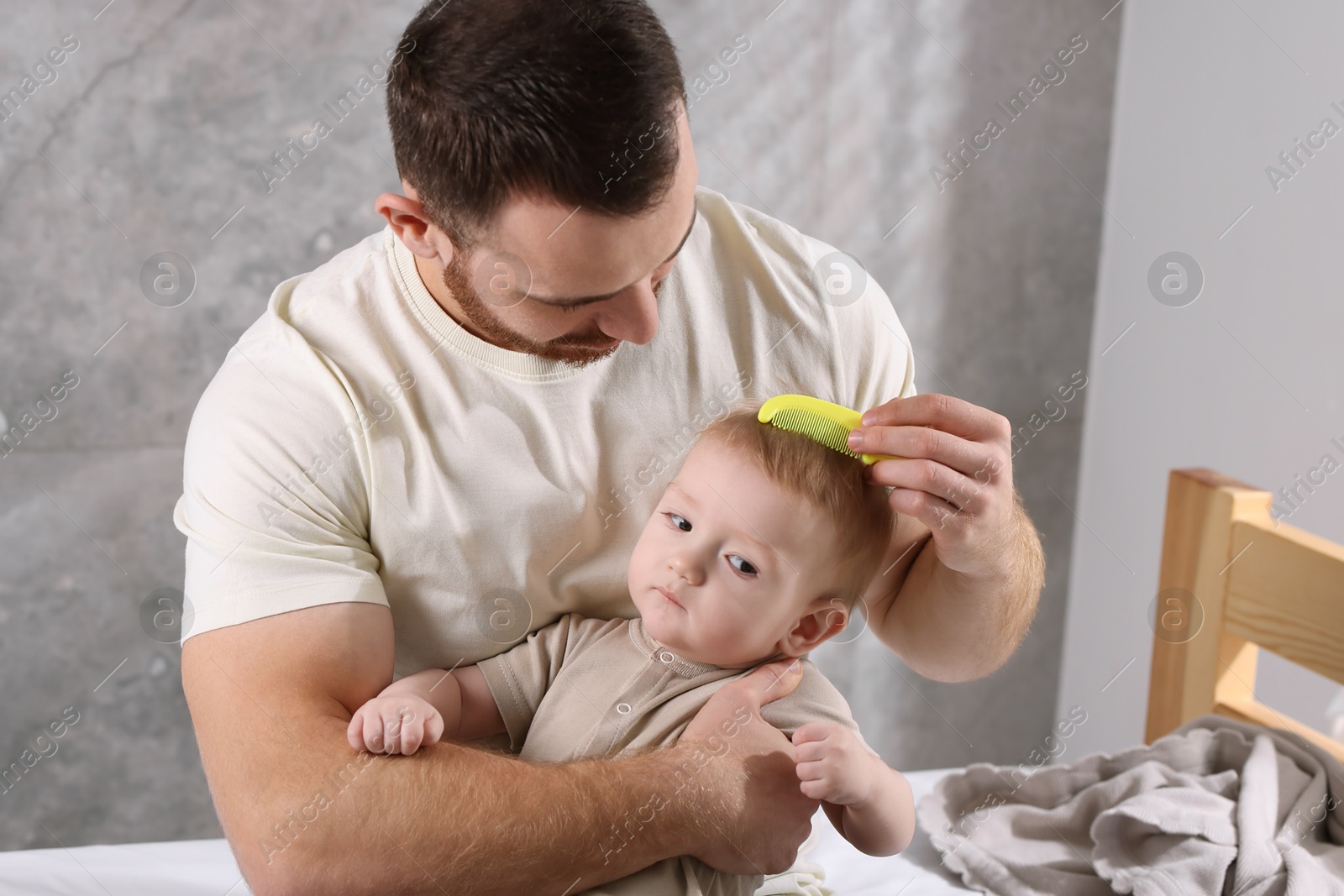 Photo of Man brushing hair of his little baby on bed indoors