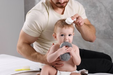 Photo of Man brushing hair of his little baby indoors, closeup