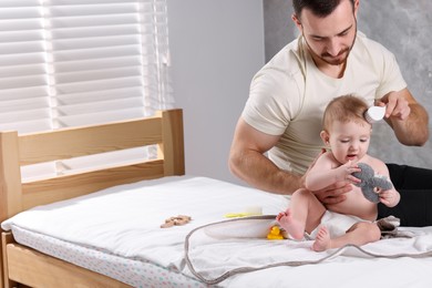 Photo of Man brushing hair of his little baby on bed indoors, space for text