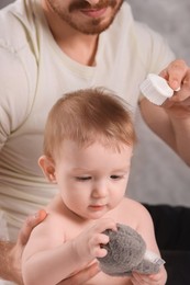 Photo of Man brushing hair of his little baby indoors, closeup