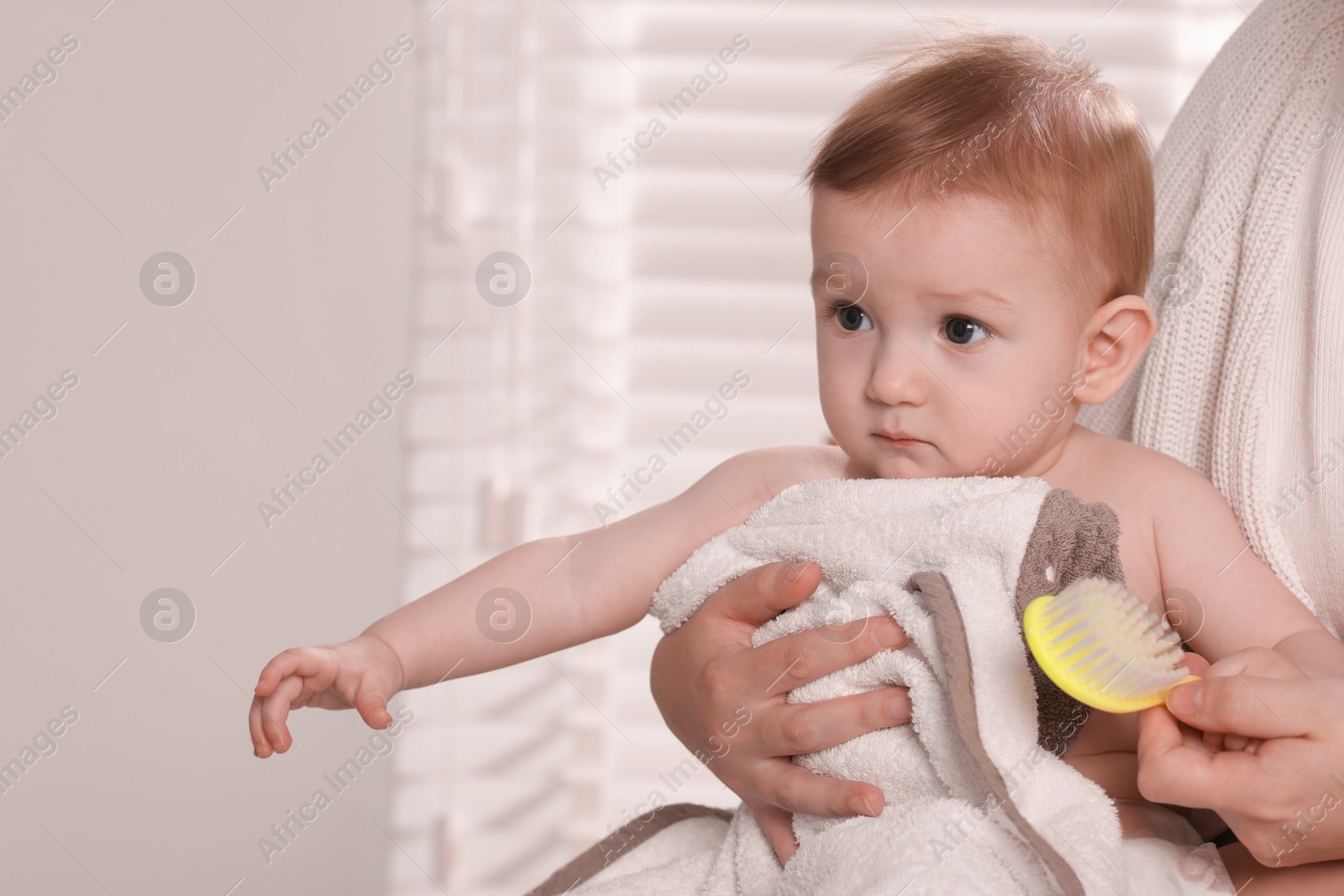 Photo of Woman brushing hair of her little baby indoors, closeup. Space for text