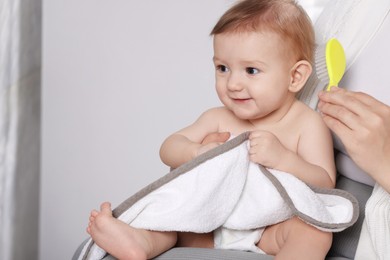 Photo of Woman brushing hair of her little baby indoors, closeup. Space for text