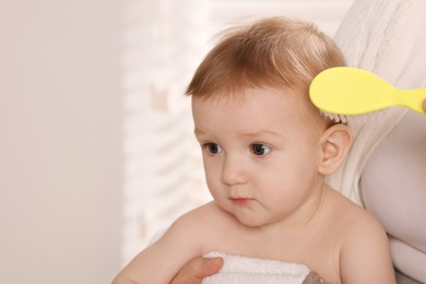 Photo of Woman brushing hair of her little baby indoors, closeup. Space for text