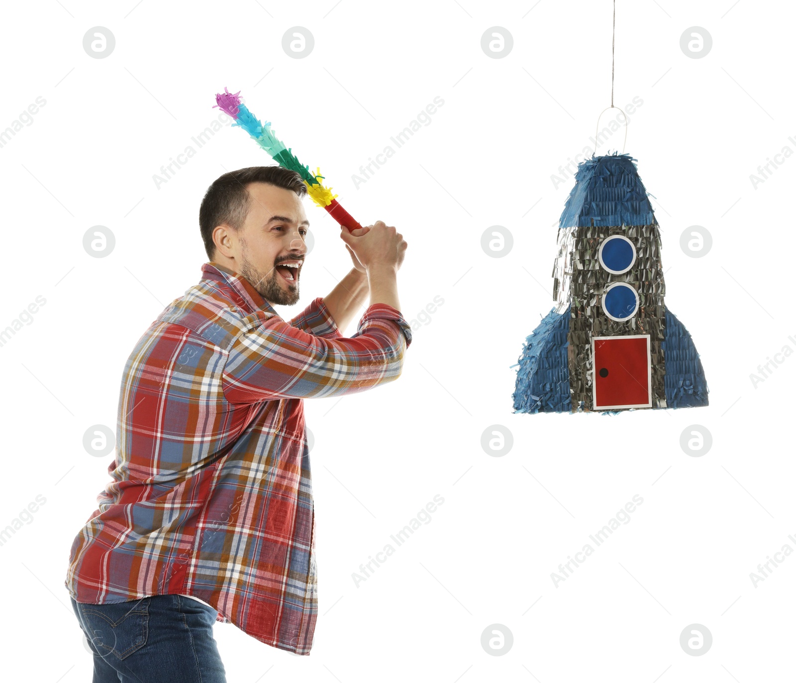 Photo of Emotional man hitting rocket shaped pinata with stick on white background