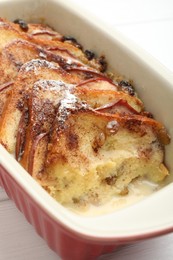 Photo of Freshly baked bread pudding in baking dish on white wooden table, closeup