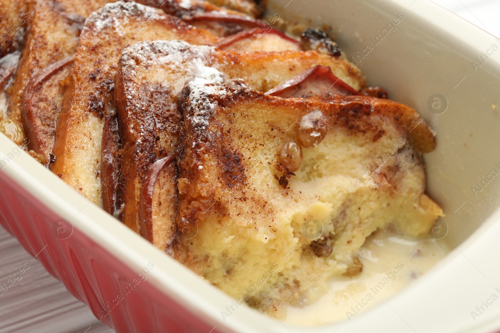 Photo of Freshly baked bread pudding in baking dish on white wooden table, closeup