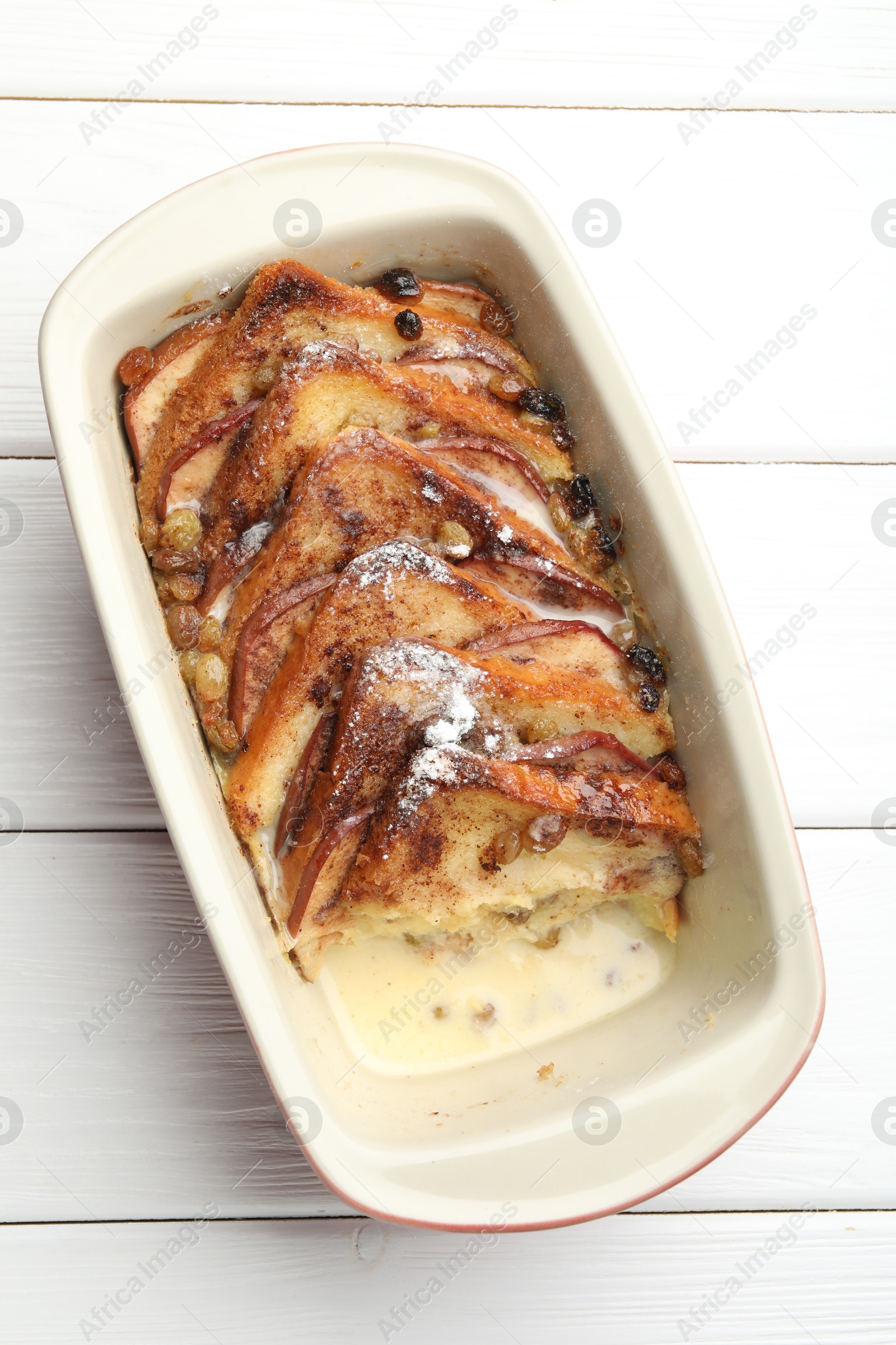 Photo of Freshly baked bread pudding in baking dish on white wooden table, top view