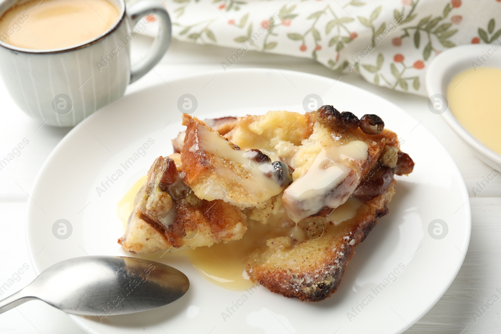 Photo of Freshly baked bread pudding and spoon on white wooden table, closeup