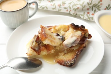 Photo of Freshly baked bread pudding and spoon on white wooden table, closeup