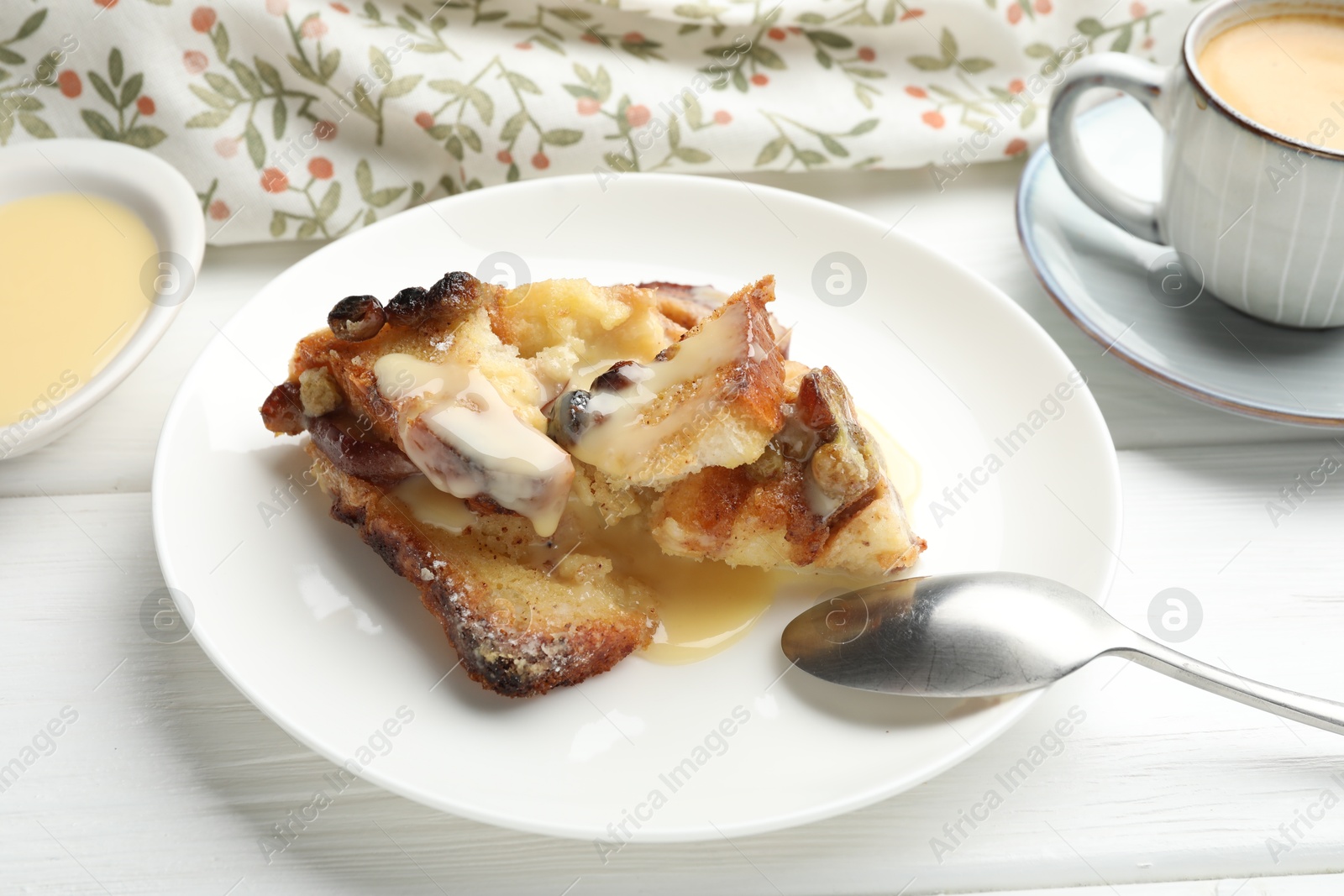 Photo of Freshly baked bread pudding and spoon on white wooden table, closeup