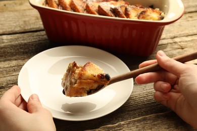 Photo of Woman eating tasty bread pudding at wooden table, closeup