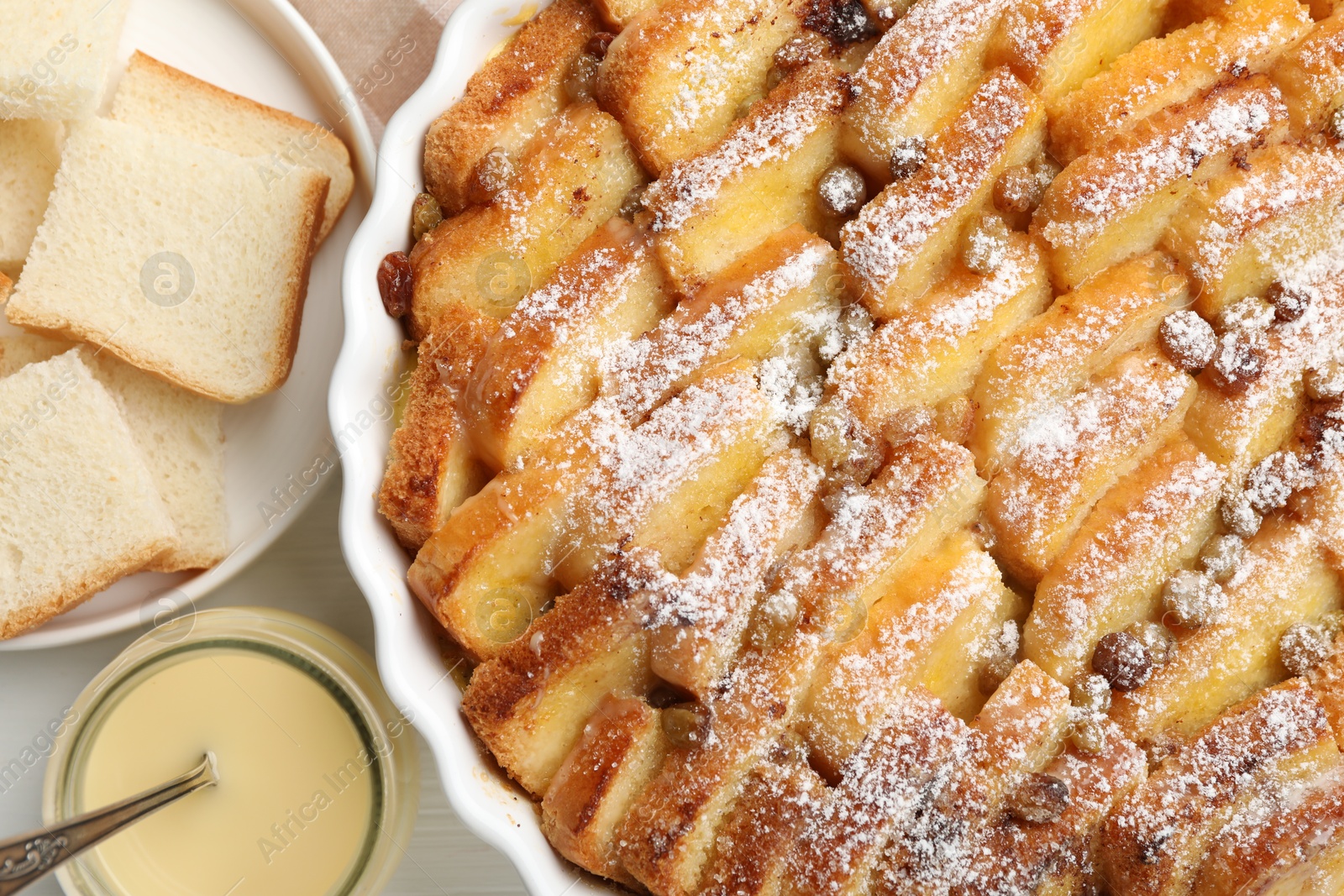 Photo of Delicious bread pudding with raisins and powdered sugar on white table