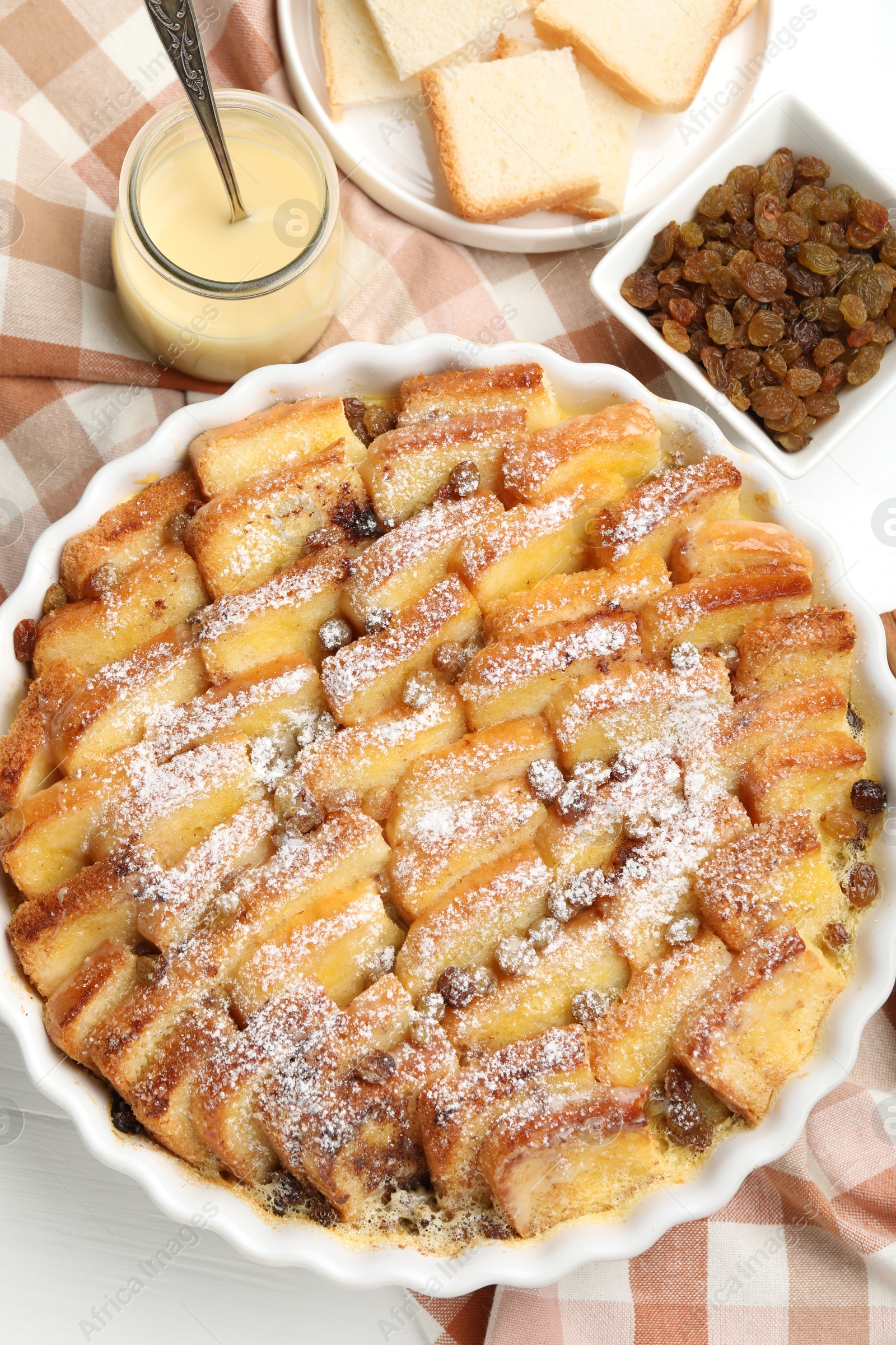 Photo of Delicious bread pudding with raisins and powdered sugar on white table