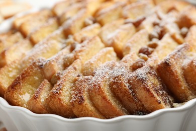 Photo of Delicious bread pudding with raisins and powdered sugar in dish, closeup